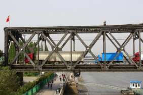 Truk melintasi jembatan yang menghubungan antara Korea Utara dan China di perbatasan Dandong, China. China dikabarkan telah memulihkan lalu lintas barang kereta api dengan Korea Utara pada Senin 17 Januari 2022.