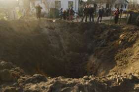 Orang-orang melihat kawah ledakan di desa Horodnya, wilayah Chernihiv, Ukraina, Kamis, 14 April 2022.