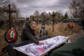 Vova, 10, melihat jenazah ibunya, Maryna, yang terbaring di peti mati saat ayahnya, Ivan Drahun, berdoa saat pemakamannya di Bucha, di pinggiran Kyiv, Ukraina, pada Rabu, 20 April 2022.