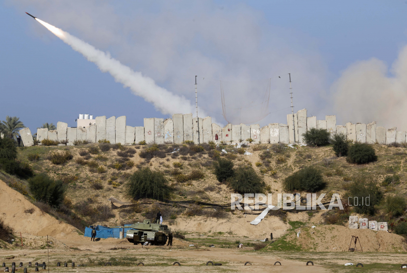 Militan Palestina berdiri di sekitar replika tank sambil menonton roket yang ditembakkan selama latihan militer yang diselenggarakan oleh faksi militer di luar Kota Gaza, Selasa, 29 Desember 2020.