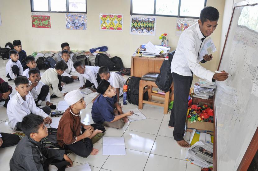 Seorang guru memberikan materi pelajaran kepada sejumlah murid yang belajar tidak menggunakan kursi dan meja belajar di Sekolah Dasar Negeri 05 Mekarsari, Tambun, Kabupaten Bekasi, Jawa Barat, Rabu (27/7/2022). Menurut keterangan orang tua murid, kondisi tersebut telah berlangsung selama tujuh bulan.