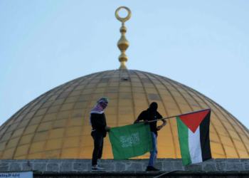 Warga Palestina bertopeng membawa bendera Palestina dan Hamas saat perayaan Idul Fitri di sebelah Masjid Kubah Batu di kompleks Masjid Al-Aqsa di Kota Tua Yerusalem, 2 Mei 2022. Kelompok militan Palestina Hamas mengancam tindakan bermusuhan terhadap Israel atas apa yang disebutnya