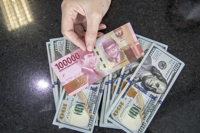 Petugas menunjukan uang pecahan Rupiah dan dolar AS di gerai penukaran mata uang asing. ilustrasi