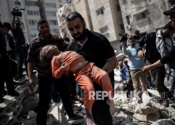 Seorang pria Palestina membawa seorang anak yang meninggal dibawa dari puing-puing bangunan tempat tinggal yang hancur setelah serangan udara Israel di Kota Gaza, Ahad (16/5). Kemenlu Palestina: Israel Sengaja Bunuh 44 Anak Palestina selama 2022