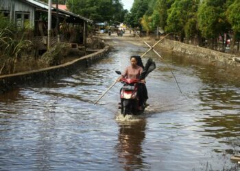 Dua pengendara motor melintasi genangan banjir (ilustrasi). Badan Nasional Penanggulangan Bencana (BNPB) memantau kejadian banjir yang merendam enam desa di Kabupaten Sintang, Kalimantan Barat sejak, Ahad (2/10/2022).