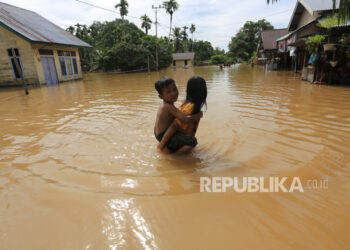 Anak-anak berjalan di depan rumahnya yang terendam banjir (ilustrasi)