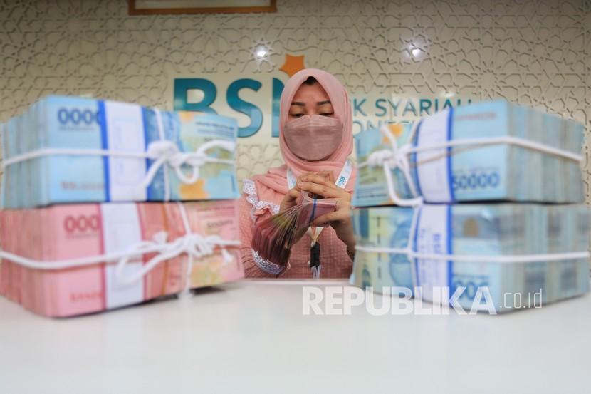 Karyawati Bank Syariah Indonesia (BSI) menghitung uang rupiah (ilustrasi). PT  Bank Syariah Indonesia Tbk (BSI) dan Direktorat Jenderal Anggaran Kementerian Keuangan RI menandatangani perjanjian kerja sama payroll.