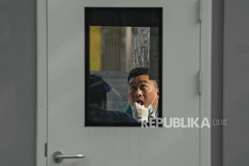 Seorang pria melakukan swab tenggorokan COVID-19 secara rutin di tempat pengujian virus corona di Beijing, Rabu, 2 November 2022. Pemerintah Kota Beijing menghadapi situasi yang menyulitkan dalam menangani pandemi COVID-19.