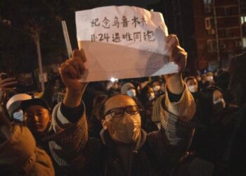 Seorang pengunjuk rasa mengangkat tanda bertuliskan Peringati Urumqi 24 November rekan senegaranya yang meninggal di Beijing, Ahad, 27 November 2022. Para pengunjuk rasa yang marah dengan tindakan anti-virus yang ketat menyerukan agar pemimpin kuat China itu mengundurkan diri, teguran yang belum pernah terjadi sebelumnya dari pihak berwenang di setidaknya delapan kota berjuang untuk menekan demonstrasi hari Minggu yang merupakan tantangan langsung yang jarang terjadi pada Partai Komunis yang berkuasa.
