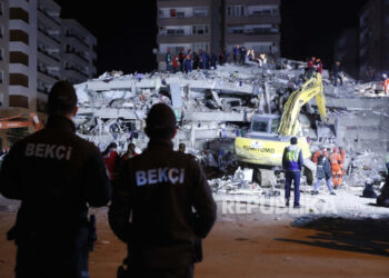 Anggota layanan keamanan mengawasi saat anggota layanan penyelamatan mencari korban di puing-puing bangunan yang runtuh di Izmir, Turki, Sabtu pagi, 31 Oktober 2020. Gempa bumi berkekuatan 5,9 skala richter (SR) melanda barat laut Turki pada Rabu dini hari.