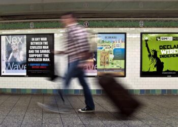 Seorang penumpang berjalan melewati sebuah poster anti-Islam yang dipasang di stasiun kereta bawah tanah Times Square, New York, Senin (24/9). Polisi New York Selidiki Serangan Terhadap Wanita Muslim di Kereta. (Bebeto Matthews/AP)