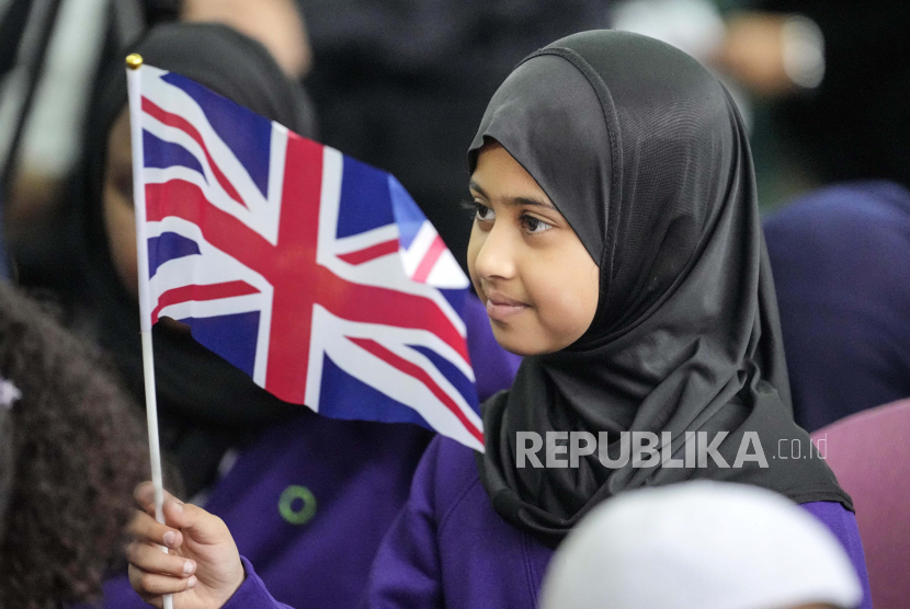 Seorang gadis dari Sekolah Zaitun mengibarkan bendera Inggris selama peringatan Muslim nasional untuk mendiang Ratu Elizabeth II di masjid pusat di London, Inggris, Kamis, 15 September 2022. Ratu Elizabeth II, raja terlama yang memerintah Inggris meninggal Kamis 8 September 2022, setelah 70 tahun bertahta.