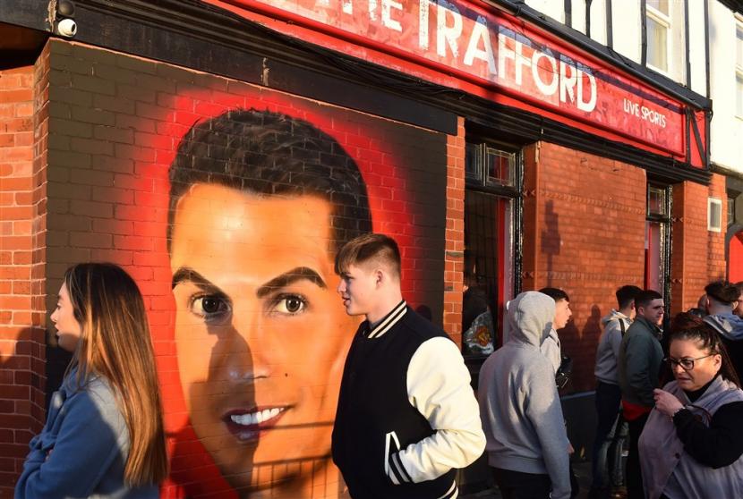 Fans berjalan melewati mural Cristiano Ronaldo di dinding pub di luar stadion Old Trafford sebelum kick off pertandingan sepak bola grup F Liga Champions UEFA antara Manchester United dan Villarreal CF di Manchester, Inggris, 29 September 2021.