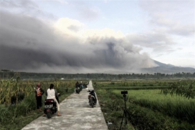 Gunung Semeru memuntahkan material vulkanik ke udara saat orang-orang menyaksikan erupsi di Lumajang, Jawa Timur, Ahad, 4 Desember 2022. Pusat Vulkanologi dan Mitigasi Bencana Geologi (PVMBG) memaparkan alasan meningkatkan status Gunung Semeru di Jawa Timur menjadi Level IV atau Awas. FOTO/EPA-EFE/STRINGER