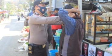 Petugas kepolisian kota Sukabumi sedang memasangkan masker pada salah seorang pedagang di pasar kota Sukabumi (ilustrasi)