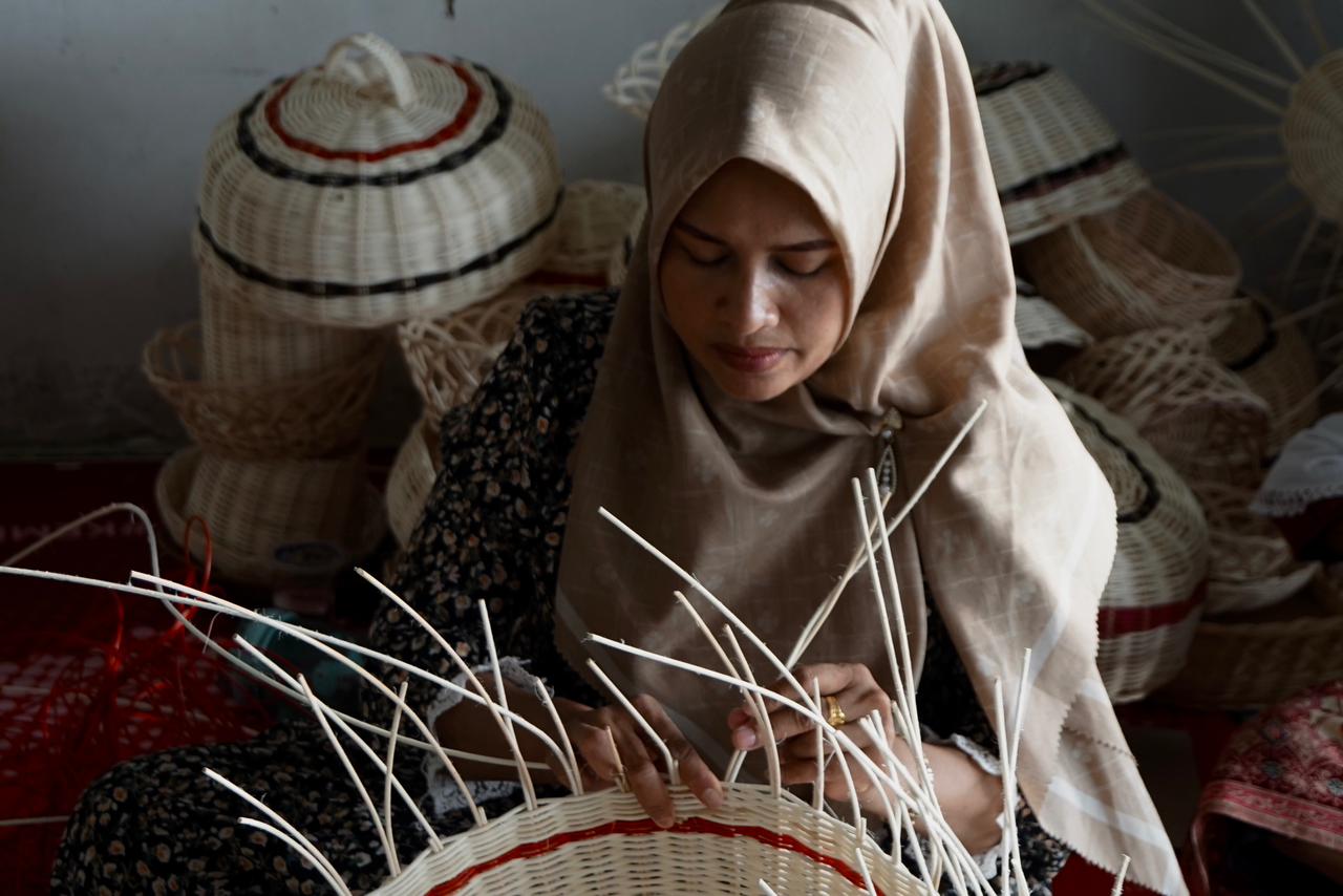Seorang Ibu rumah tangga sibuk merangkai batang rotan, menyambung batang demi batang menjadi piring rotan, tudung saji dan keranjang buah. FOTO/HAI/Fendra Tryshanie. Ⓒ Hak cipta foto di atas dikembalikan sesungguhnya kepada pemilik foto