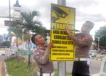 Personel Ditlantas Polda Aceh memasang papan rambu peringatan electronic traffic law enforcement (ETLE) di sejumlah titik traffic light di Kota Banda Aceh, Jumat, 3 Mei 2024. FOTO/Orinews/Maulya. Ⓒ Hak cipta foto di atas dikembalikan sesungguhnya kepada pemilik foto