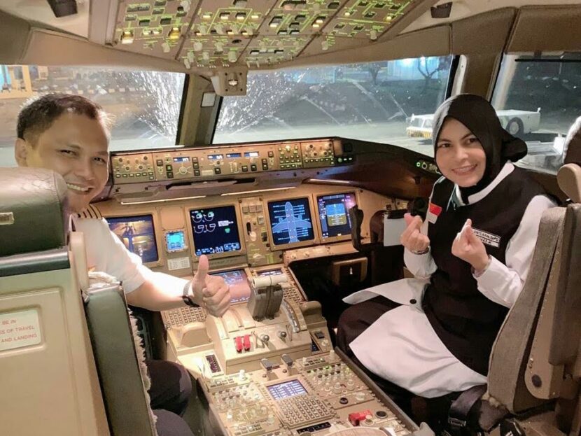 dr. Junita, M.Kes., Sp.PD., di kokpit pesawat komersial saat perjalanan musim haji 2022—momen hangat di tengah tugas mulia mendampingi jamaah haji Aceh