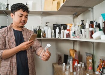 Seorang pria sedang memoto botol Parfum. FOTO/Net. Ⓒ Hak cipta foto di atas dikembalikan sesungguhnya kepada pemilik foto